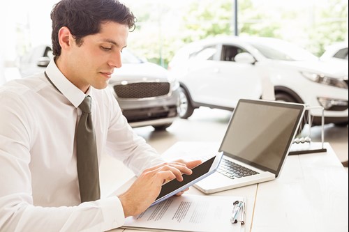 man op computer bij autodealer